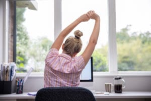 Woman stretching back at her desk